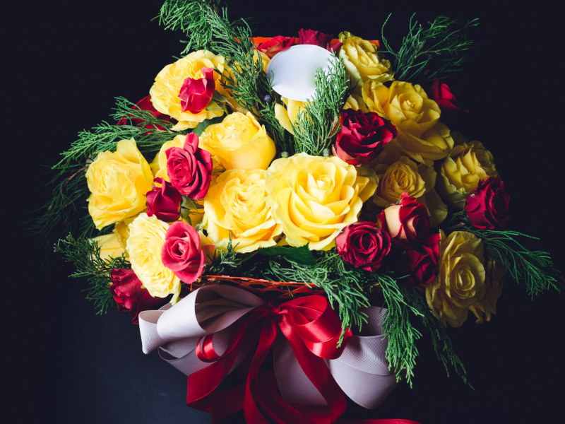 Red and white ribbons twine bouquet of red and yellow roses