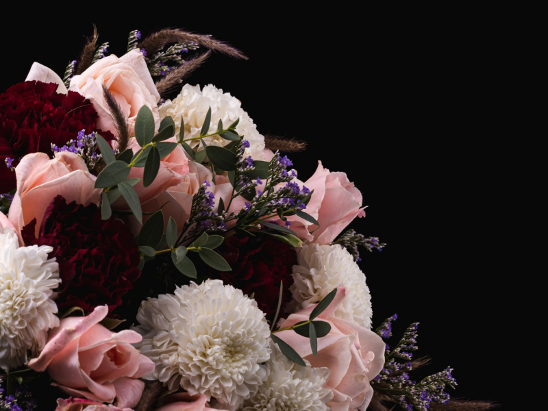 A vertical shot of a luxurious bouquet of pink roses and white, red dahlias on a black background